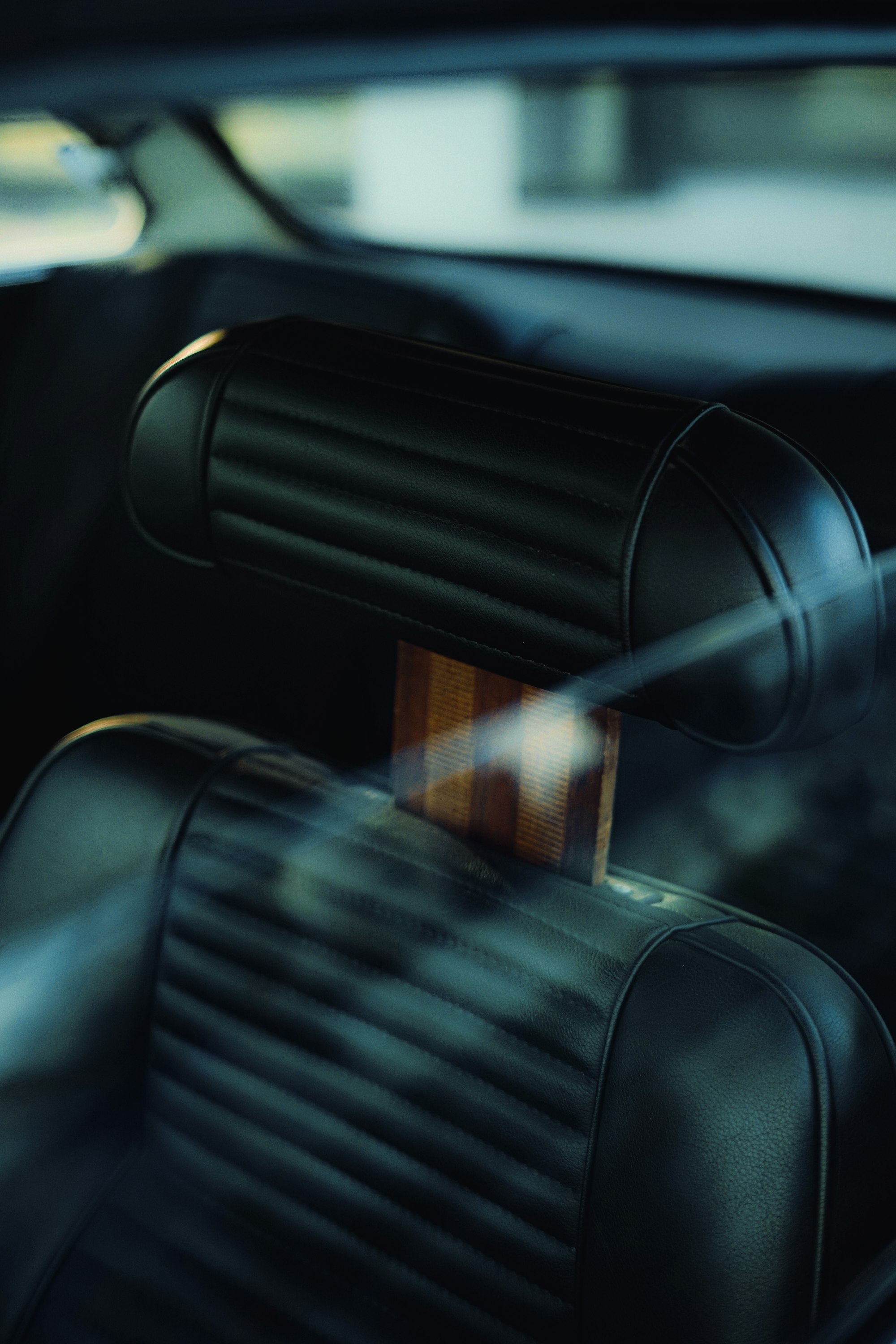 Close-up of a black quilted leather headrest with a walnut stem