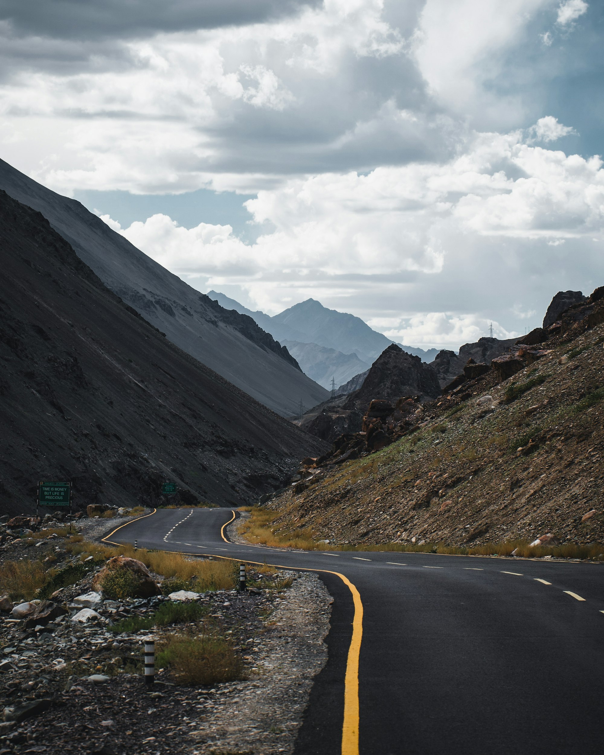 An empty mountain road curving between steep rocky slopes